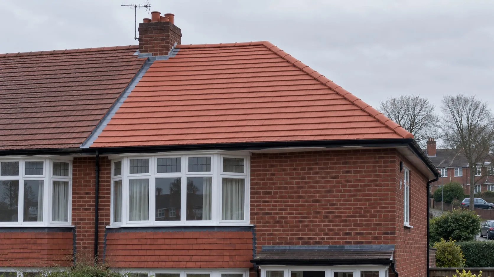 A completed clay plain-tile roof on a 1930s semi, even terracotta courses and a crisp dry ridge.