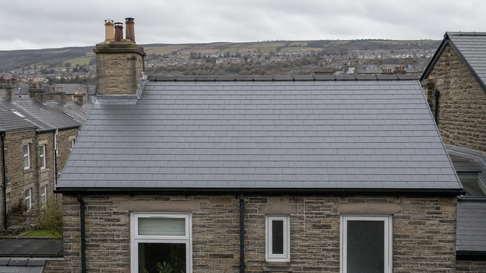 A completed natural slate re-roof on a Victorian stone terrace, even courses and a straight new ridge.